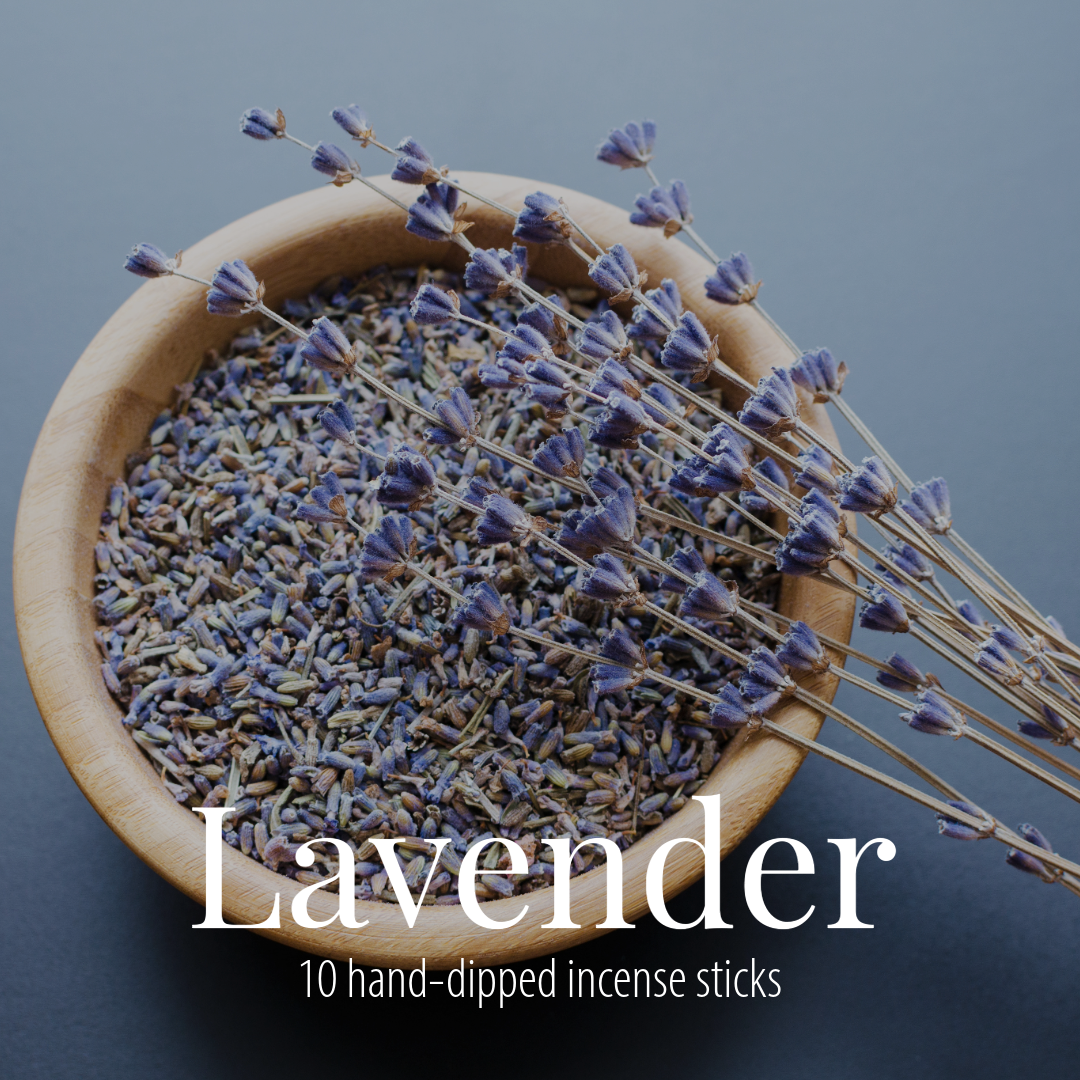 A wooden bowl of dried lavender buds with dried stems laid across it, photographed on a slate blue-grey background, with the Lavender label overlaid in white