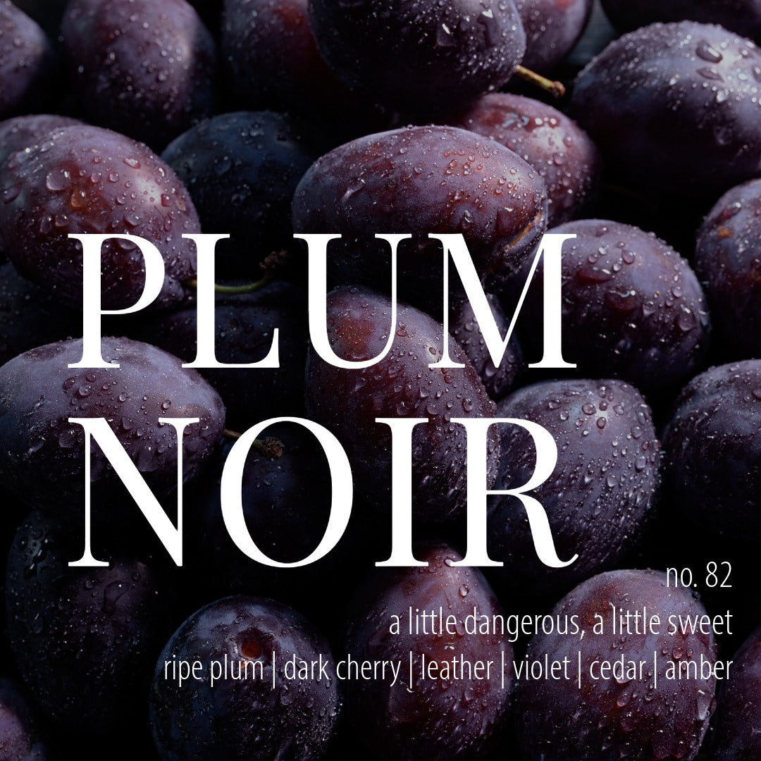 a background of wet plum fruit with white text that reads plum noir, number 82, a little dangerous, a little sweet, ripe plum, dark cherry, leather, violet, cedar, and amber