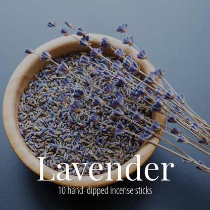 A wooden bowl of dried lavender buds with dried stems laid across it, photographed on a slate blue-grey background, with the Lavender label overlaid in white