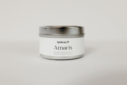 Silver candle tin with lid. White rectangular label that reads Amaris and Apothecary 19.